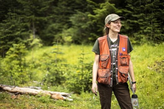a student stands in a meadow wearing a safety vest