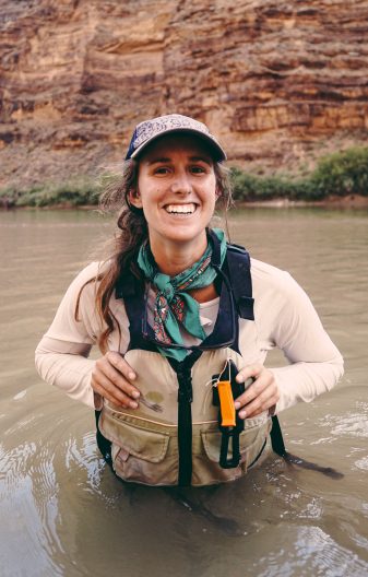 a women in a lifevest stands in a river