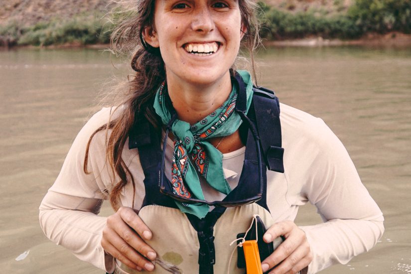 a women in a lifevest stands in a river