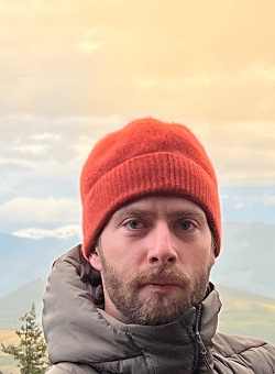 man in hat stands on a mountain