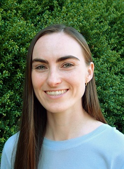 a woman smiles in front of a bush