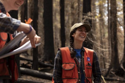 person in a orange vest laughing in a forest