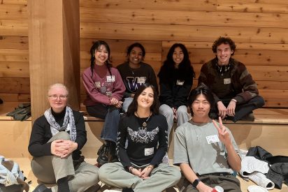 Students at a holiday party with a wood paneled background.