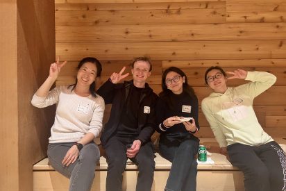 People holding up the peace sign with a wood paneled background.
