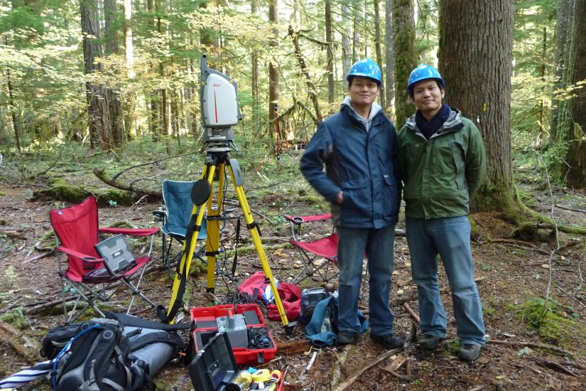 Guang Zhen and Akira Kato wear hard hats in the woods at Wind River.