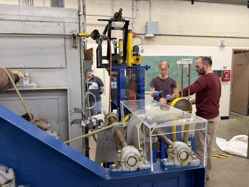 Associate Professor Anthony Dichiara guides Kira Stewart (left) while operating a paper machine. 
